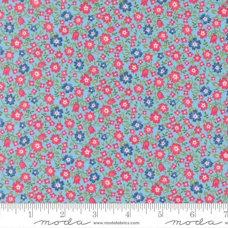 The image is a fabric with a floral pattern in shades of blue and red. The pattern consists of small flowers and leaves scattered across the fabric, creating a vibrant and colorful design.