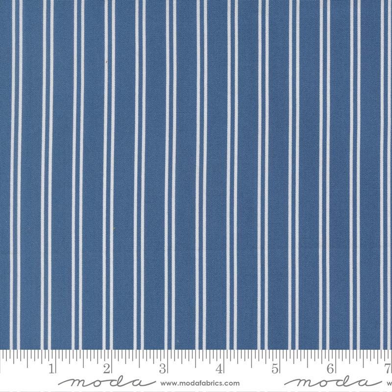 a close-up view of a fabric with vertical white stripes. The fabric appears to be a solid blue color, with the white stripes contrasting against the blue background. The image does not contain any text or additional objects, and the focus is solely on the fabric and its striped pattern.