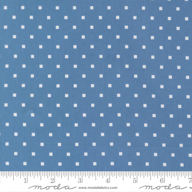 a close-up view of a fabric with a blue background and white polka dots. The fabric appears to be a type of textile, possibly used for clothing or home decor.