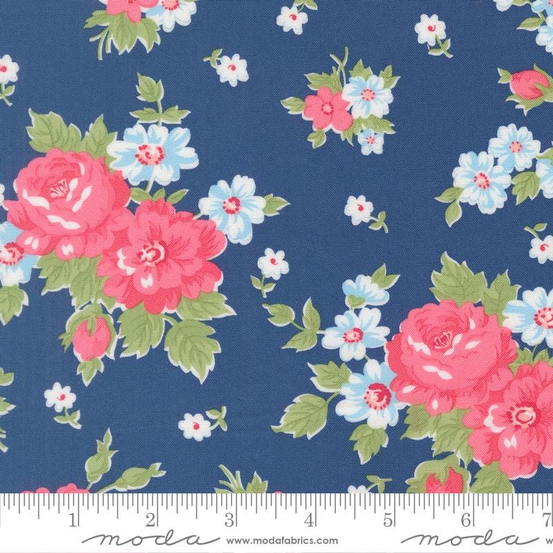 a close-up view of a fabric with a floral pattern. The fabric has a dark blue background with pink and white flowers scattered throughout. The flowers are the main focus of the image, with some larger flowers and smaller ones interspersed among them. The fabric appears to be a textile, possibly used for clothing or home decor.