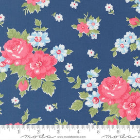 a close-up view of a fabric with a floral pattern. The fabric has a dark blue background with pink and white flowers scattered throughout. The flowers are the main focus of the image, with some larger flowers and smaller ones interspersed among them. The fabric appears to be a textile, possibly used for clothing or home decor.