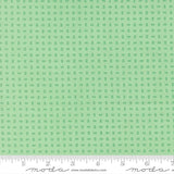 The image is a fabric with a green pattern, featuring small square shapes arranged in a grid-like pattern.