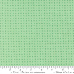 The image is a fabric with a green pattern, featuring small square shapes arranged in a grid-like pattern.