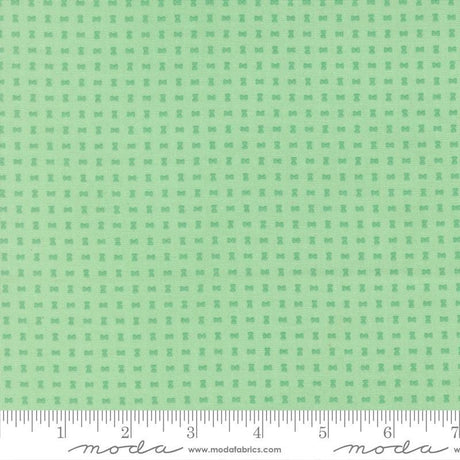 The image is a fabric with a green pattern, featuring small square shapes arranged in a grid-like pattern.