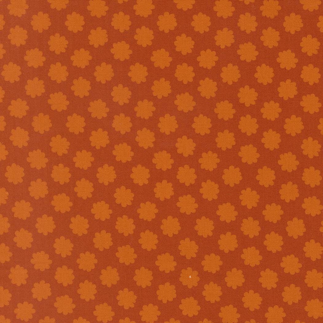 a repeating pattern of orange and brown flowers or shapes on a brown background.