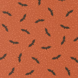 a repeating pattern of black bats against a textured orange background with small white dots, creating a visually striking and festive design.