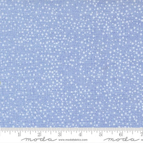 The image is a close-up of a fabric with a light blue background and white dots, resembling a speckled or speckled pattern.