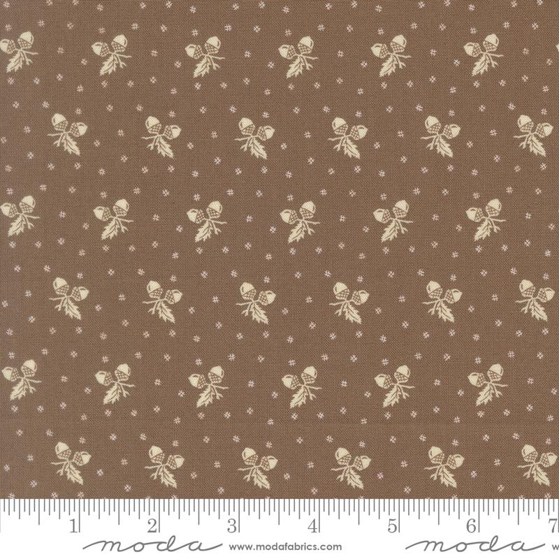 a brown fabric with a repeating pattern of white acorns and leaves. The pattern is composed of small white dots, creating a visually appealing and intricate design. The fabric appears to be a piece of clothing or textile, with the acorn and leaf motifs possibly used for embellishment or decoration.