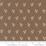 a brown fabric with a repeating pattern of white acorns and leaves. The pattern is composed of small white dots, creating a visually appealing and intricate design. The fabric appears to be a piece of clothing or textile, with the acorn and leaf motifs possibly used for embellishment or decoration.