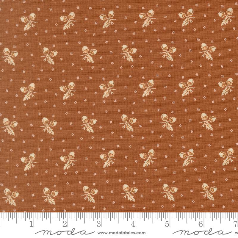 The image is a fabric with a repeating pattern of brown and white acorns or leaves, creating a visually appealing and textured design.