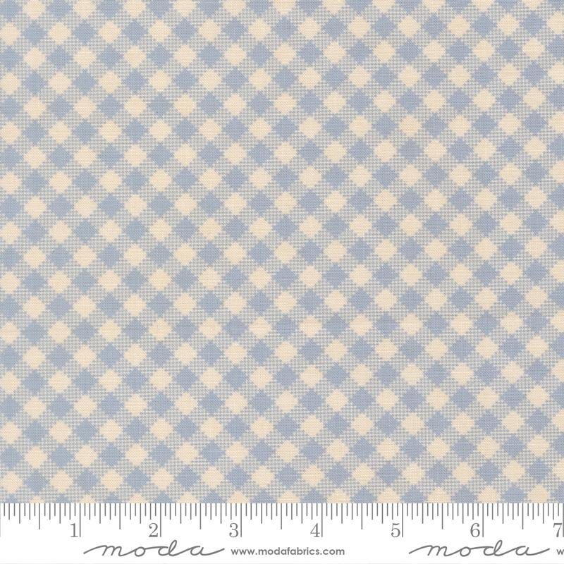 a fabric with a blue and beige checkered pattern. The fabric appears to be a light blue color, and the pattern consists of small squares or rectangles arranged in a diagonal grid-like pattern. The fabric is laid out flat, and there is a ruler visible at the bottom of the image.