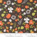 The image is a fabric with a floral pattern featuring various flowers and leaves in shades of orange, white, and green against a dark background.