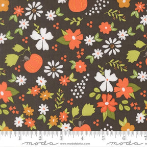 The image is a fabric with a floral pattern featuring various flowers and leaves in shades of orange, white, and green against a dark background.