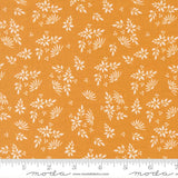 a fabric with a repeating pattern of white flowers and leaves on an orange background. The pattern is spread across the fabric, creating a visually appealing design.