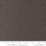 a close-up view of a fabric with a dark brown color and small white dots or specks covering the entire surface.