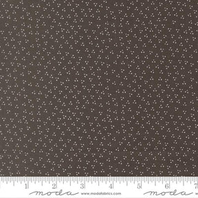 a close-up view of a fabric with a dark brown color and small white dots or specks covering the entire surface.