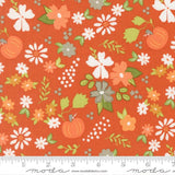 The image is a vibrant fabric with a repeating pattern of orange, white, and green flowers and leaves, along with orange pumpkins. The pattern is spread across the fabric, creating a lively and colorful design.