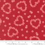 a red fabric with a pattern of pink hearts and flowers scattered across it.