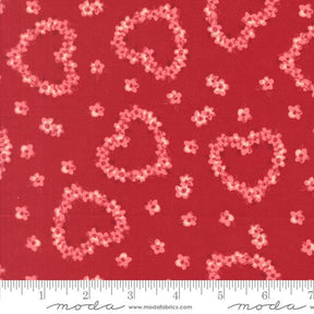 a red fabric with a pattern of pink hearts and flowers scattered across it.