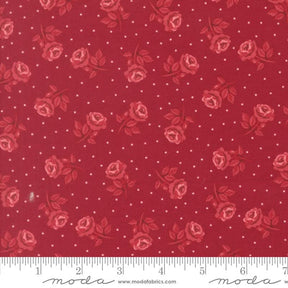a red fabric with a repeating pattern of red roses and white dots.