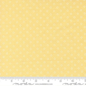 The image is a close-up of a fabric with a yellow background and white polka dots.