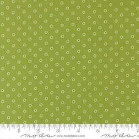 a close-up view of a fabric with a green background and white polka dots. The fabric appears to be a type of textile, possibly used for clothing or home decor.