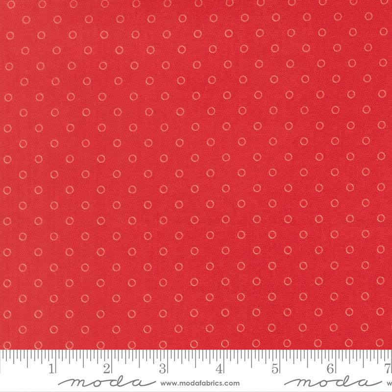 The image is a close-up of a red fabric with white polka dots, and there is a ruler for scale at the bottom of the image.