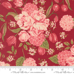 a close-up view of a vibrant red fabric adorned with a floral pattern. The pattern consists of various pink and red flowers, including roses, hydrangeas, and tulips, interspersed with green leaves. The fabric appears to be a textile or fabric material, with a ruler visible in the bottom right corner for scale.