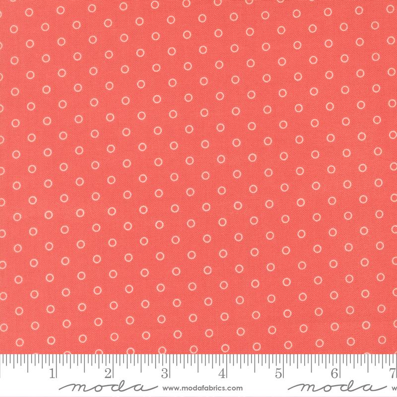 a close-up view of a fabric with a repeating pattern of small white circles against a bright red background.