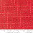 The image is a close-up of a red fabric with a grid pattern of small white dots.