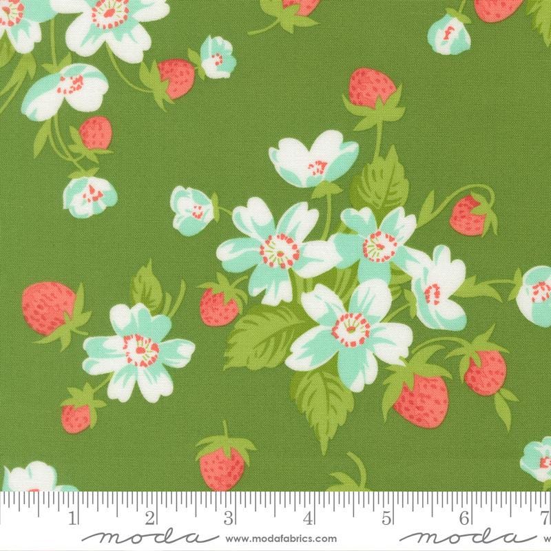 a vibrant green fabric adorned with a repeating pattern of white and red flowers, along with green leaves and red berries. The fabric appears to be a textile or fabric material, with a ruler visible in the bottom right corner for scale.
