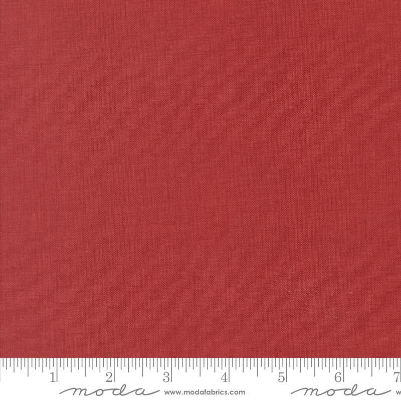 The image is a close-up of a red fabric with a ruler for scale.