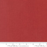 The image is a close-up of a red fabric with a ruler for scale.