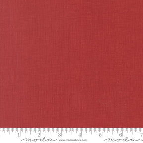 The image is a close-up of a red fabric with a ruler for scale.