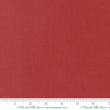 The image is a close-up of a red fabric with a ruler for scale.