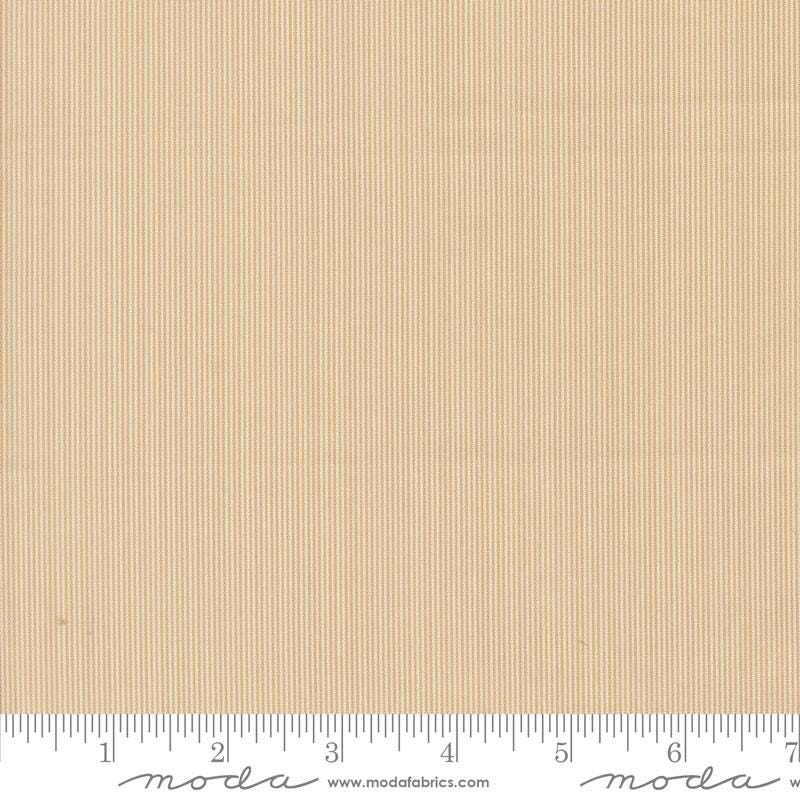 The image is a fabric swatch with a light brown color, and it is being used as a reference for measuring.