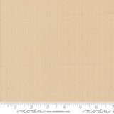 The image is a fabric swatch with a light brown color, and it is being used as a reference for measuring.