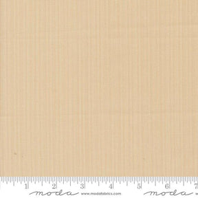 The image is a fabric swatch with a light brown color, and it is being used as a reference for measuring.