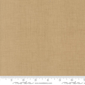 The image is a close-up of a fabric with a light brown or beige color. There is a ruler at the bottom of the image, indicating the size of the fabric in inches.