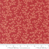 a close-up view of a fabric with a red background and a repeating pattern of small white leaves or flowers. The fabric appears to be made of a material with a floral print, and there is a ruler visible at the bottom of the image.